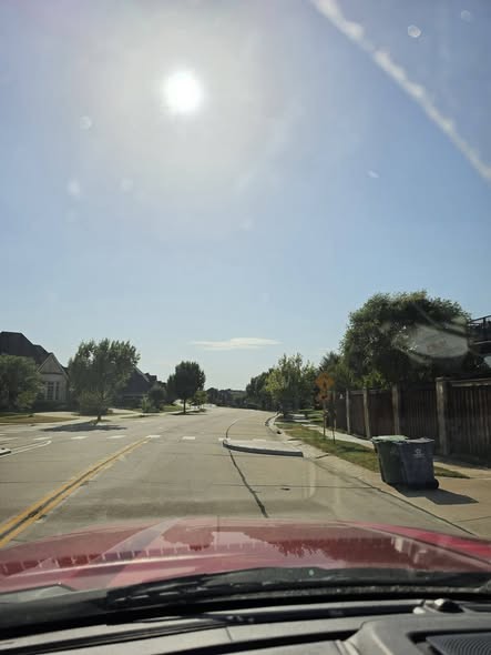 Driver-eye view along King Arthur with low afternoon sun shining directly toward the camera